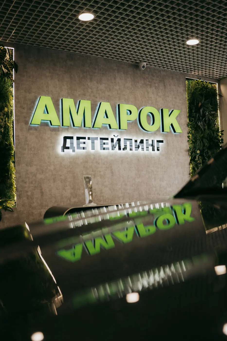 Вывеска «АМАРОК ДЕТЕЙЛИНГ» отражается в отполированном капоте чёрного автомобиля